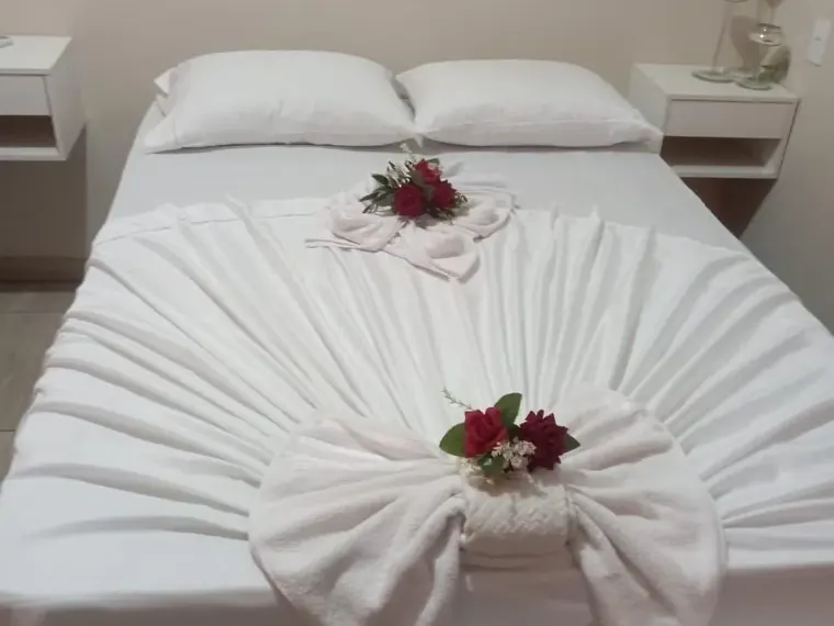 Quarto de casal com cama preparada e enxoval branco